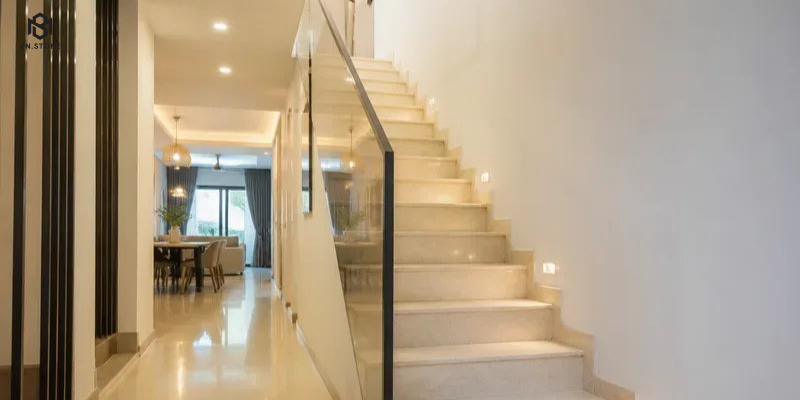 Đá cầu thang nhà ống: chọn màu, kích thước, giá và cách thi công 1 - Tổng Kho Đá Cầu thang nhà ống ốp đá sáng màu đặt sát tường biên, vế thang hẹp nhưng vẫn thoáng nhờ lan can kính